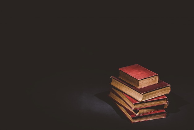 Pile de vieux livres sur fond noir, ton vintage