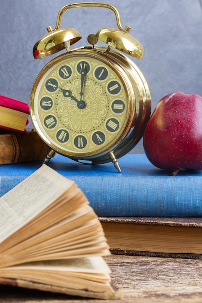 Pile de vieux livres avec réveil antique et apple