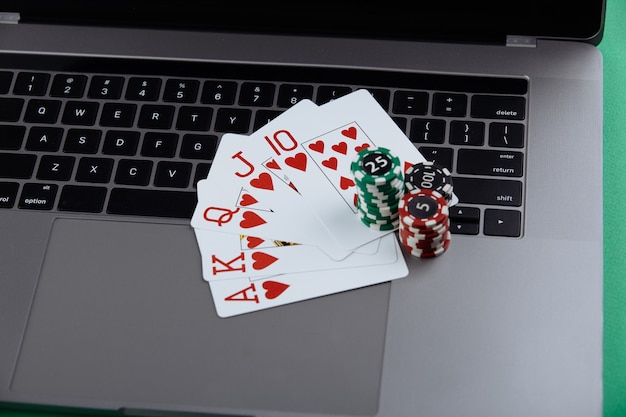 Des piles de jetons de poker et de cartes à jouer sur un ordinateur portable. Concept en ligne de casino et de poker.