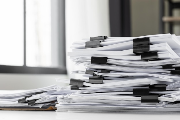 Des piles de papiers blancs fonctionnent de grandes piles de papiers empilés ensemble. Sur le bureau du bureau avec clip noir. Documents qui ne sont pas terminés. Notion d'entreprise.