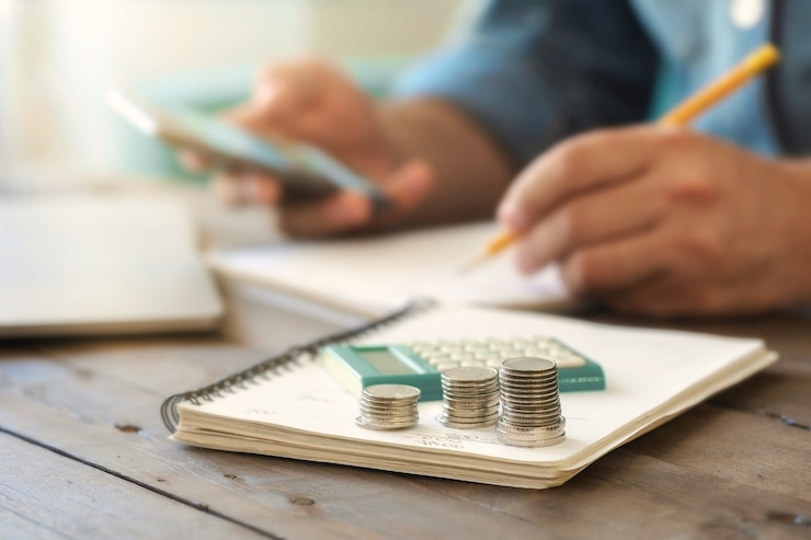 Photo des piles de pièces sur une table en bois avec une calculatrice. taxation, comptabilité à domicile ou analyse de crédit pour le concept de paiement hypothécaire