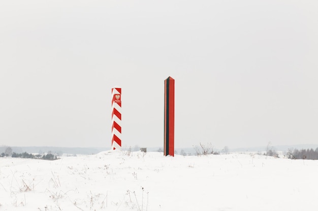 Piliers frontaliers de la Biélorussie et de la Pologne à la frontière dans un champ d'hiver