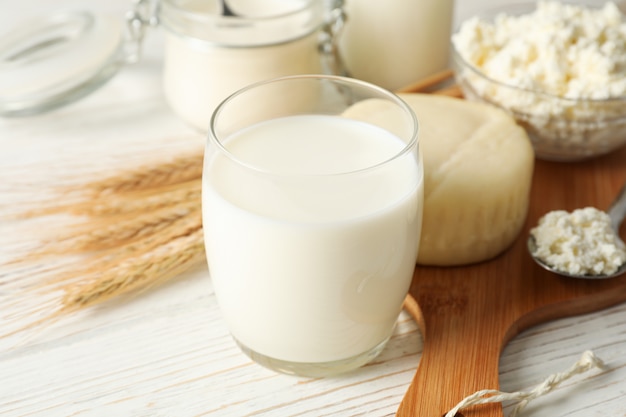 Épillets de blé, produits laitiers et planche sur fond de bois blanc