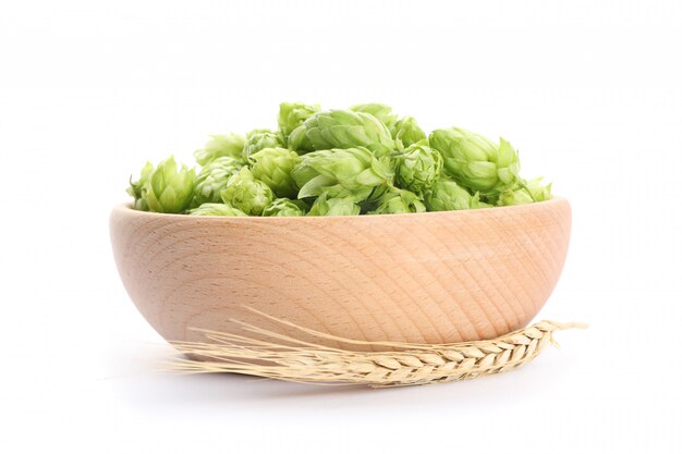 Épillets et bol en bois avec houblon isolé sur blanc