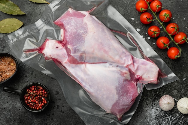 Pilon de dinde crue dans un emballage en plastique sous vide, vue de dessus à plat, sur fond de table en pierre noire noire