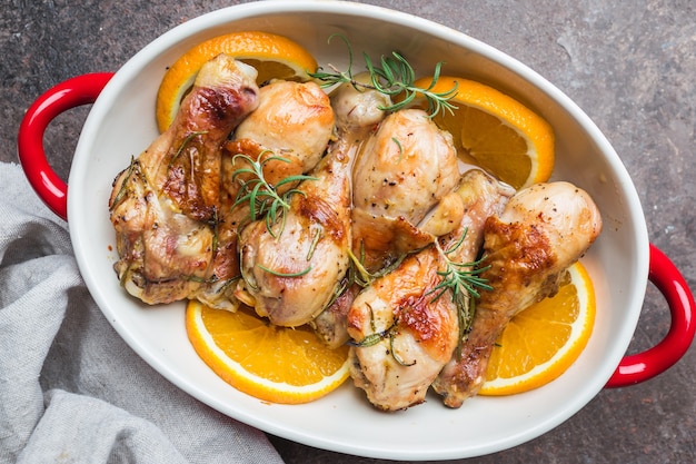 Pilon de poulet au four dans un plat à l'orange et au romarin, vue de dessus