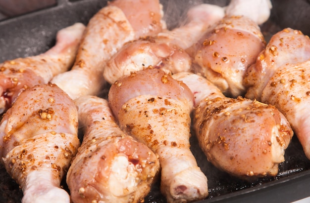 Un pilon de poulet cru sur la poêle