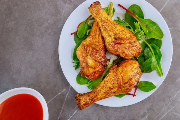 Pilon De Poulet épicé Rôti Avec Salade Et Sauce Sur Table Grise. Vue De Dessus.