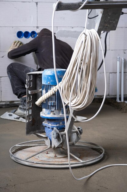 Photo pilonnage et meulage d'une chape semi-sèche par une machine à disque rotatif pour le nivellement construction d'un sol en béton dans la maison d'un maître avec un équipement spécial