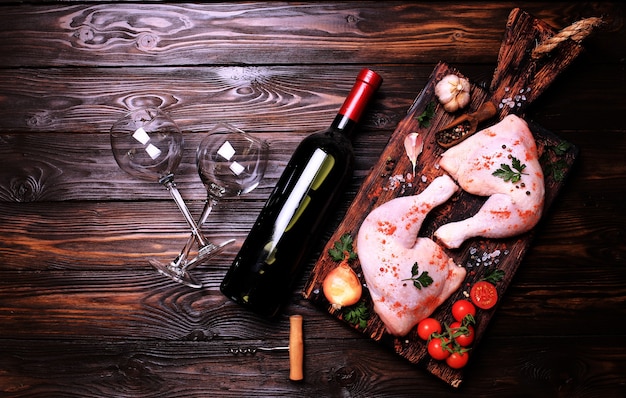 Pilons de poulet aux épices et légumes, avec une bouteille de vin rouge.