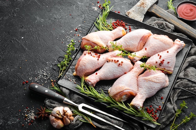 Pilons de poulet cru aux épices sur fond de pierre noire Viande Vue de dessus Style rustique