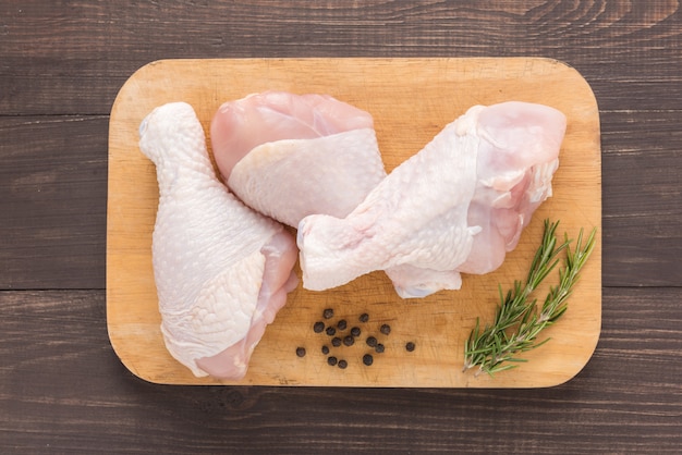 Pilons de poulet cru sur planche à découper sur table en bois