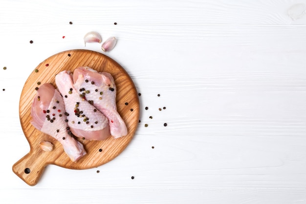 Photo pilons de poulet crus sur une planche en bois viande de poulet fraîche sur une planche à découper vue de dessus d'en haut