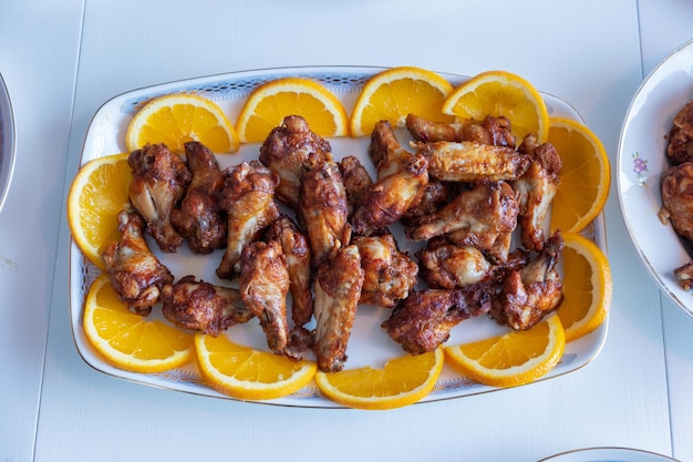 Pilons de poulet frits et grillés avec des tranches d'orange en plaque sur la table