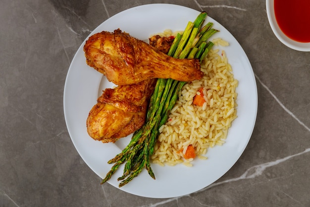 Photo pilons de poulet grillé avec riz, asperges et sauce buffalo