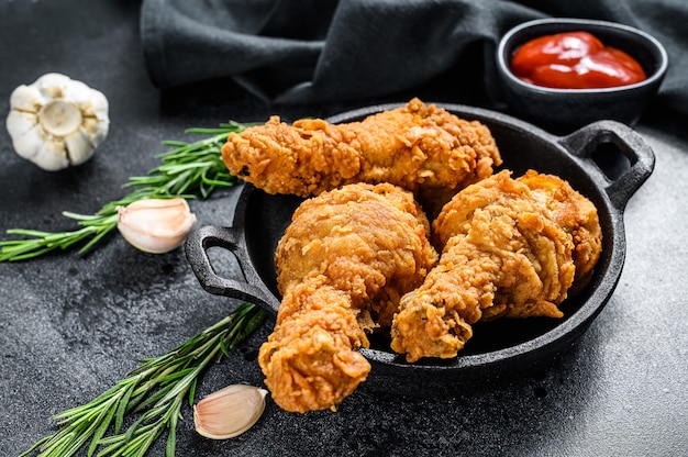 Photo pilons de poulet panés frits épicés sur tableau noir.