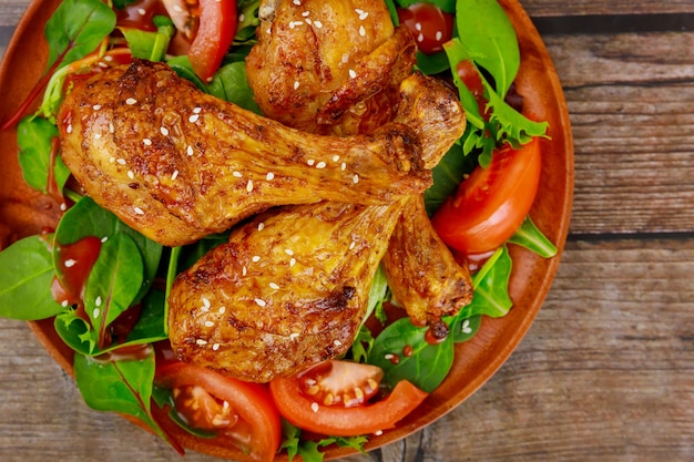 Pilons de poulet rôti avec salade sur table en bois rustique. Vue de dessus.