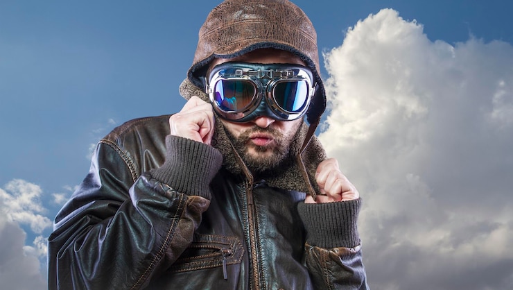 Photo pilote des années 20 avec lunettes de soleil et casque d'aviateur vintage. porte une veste en cuir, une barbe et des visages expressifs