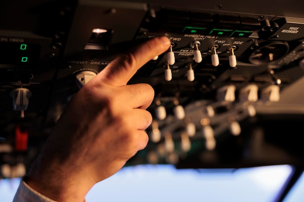 Pilote d'aviation utilisant le panneau de commande dans le cockpit pour piloter un avion en vol, en appuyant sur les boutons du moteur d'alimentation et en activant la commande du tableau de bord. Utilisation du levier et de la poignée avec pare-brise. Fermer.