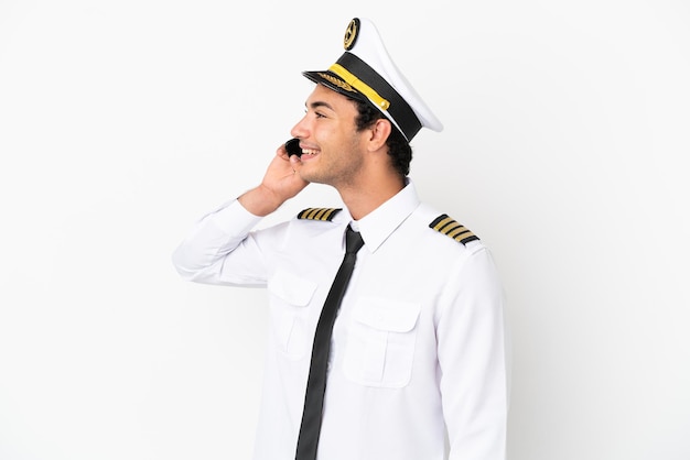 Pilote d'avion sur fond blanc isolé en gardant une conversation avec le téléphone mobile