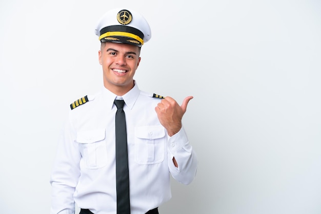 Pilote d'avion homme caucasien isolé sur fond blanc pointant vers le côté pour présenter un produit