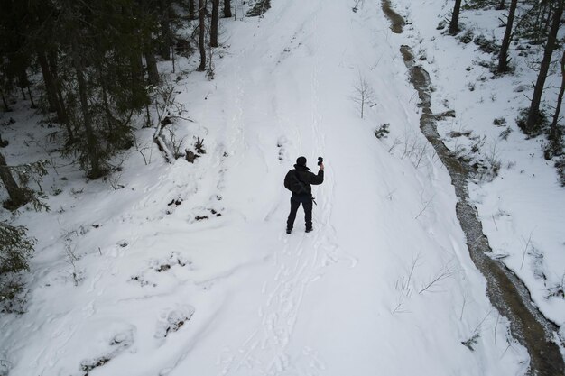 Photo un pilote de drone militaire avec un fusil ak-12 dans le dos dans une forêt d'hiver vue d'en haut