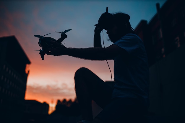 Pilote d'homme contrôlant un drone quadricoptère avec télécommande.