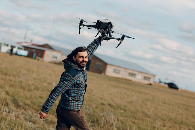 Pilote d'homme tenant un drone quadricoptère dans les mains sur le terrain extérieur