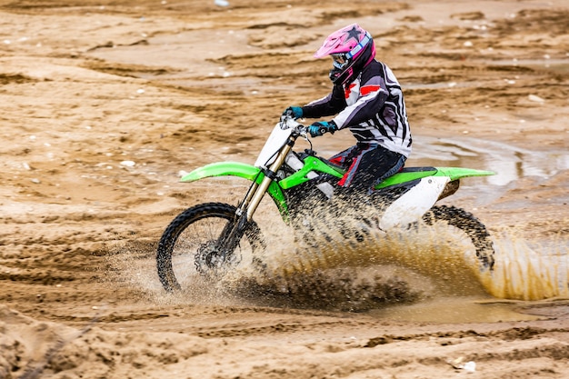 Photo pilote de moto de motocross professionnel conduit sur la piste de terre.