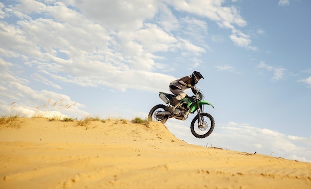 Pilote de motocross professionnel glissant sur une colline de sable