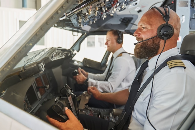 Pilotes expérimentés naviguant dans l'avion de passagers depuis leur cockpit et souriant joyeusement