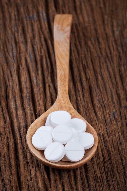 pilule blanche en cuillère sur la table en bois