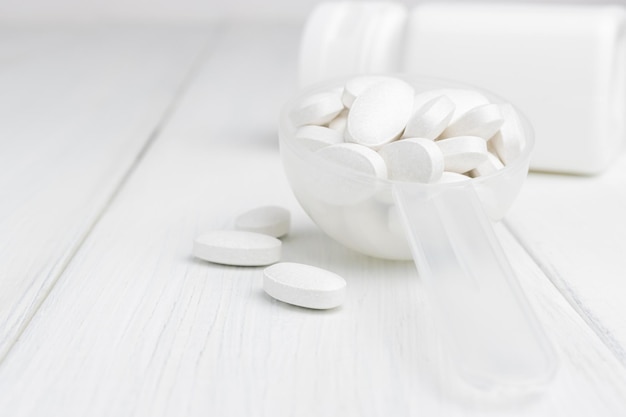Pilules blanches dans une cuillère en plastique, traitement médicamenteux, vue rapprochée