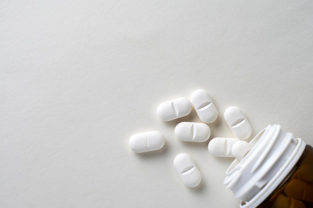 Photo des pilules blanches dispersées sur un fond blanc