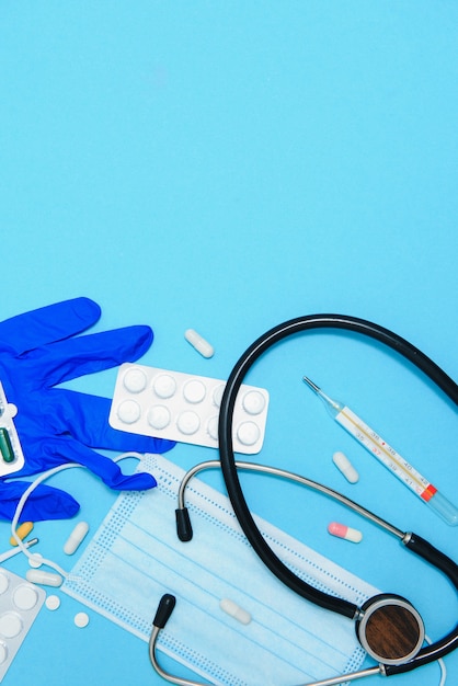 Photo pilules blanches éparpillées sur table bleue.concept médical, pharmacie et soins de santé. pilules blanches de fond bleu avec un statoscope médical, vue de dessus.