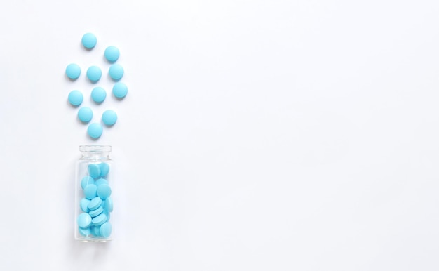Pilules bleues versées d'une bouteille en verre sur fond blanc Espace de copie complexe de vitamines