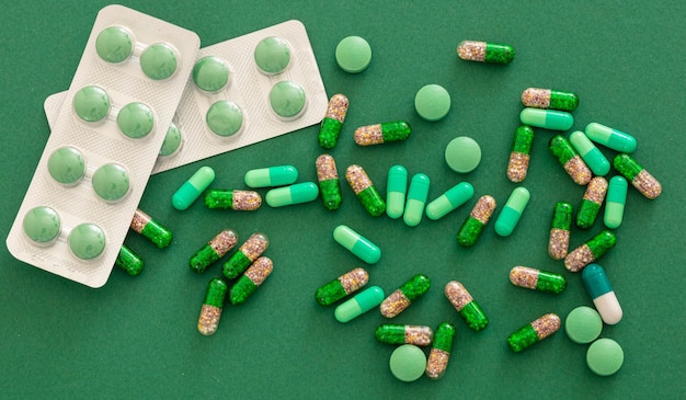 Pilules et capsules de médicaments sur fond vert Concept de pharmacie de santé