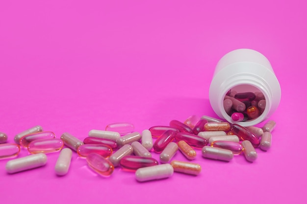 Pilules et capsules multicolores sur fond rose