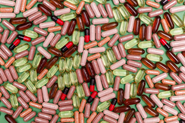 Pilules et capsules multicolores sur fond vert