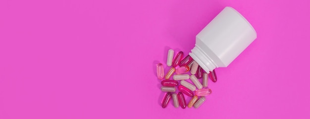 Pilules et capsules multicolores de panorama sur un fond rose