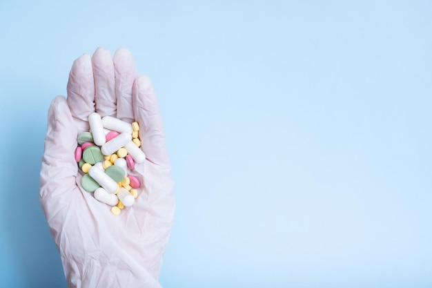 Pilules colorées dans la main gantée Concept de soins de santé et de médecine mise à plat