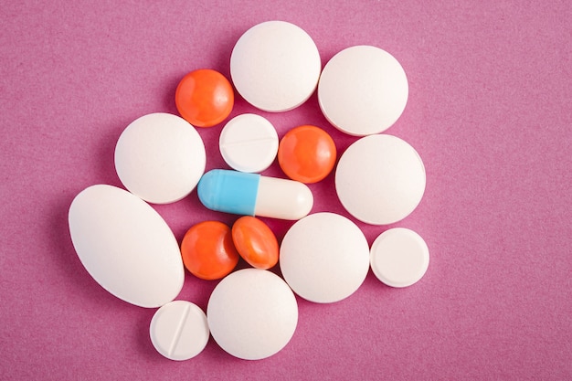 Pilules et comprimés sur fond violet rose vif, concept médical de soins de santé, antibiotiques et cure, vue de dessus
