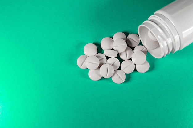 Pilules et comprimés médicaux blancs avec bouteille sur fond turquoise Photo gros plan de préparations médicales avec espace de copie