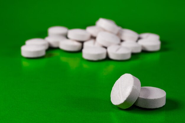Pilules et comprimés médicaux blancs avec bouteille sur fond vert Photo gros plan de préparations médicales avec espace de copie
