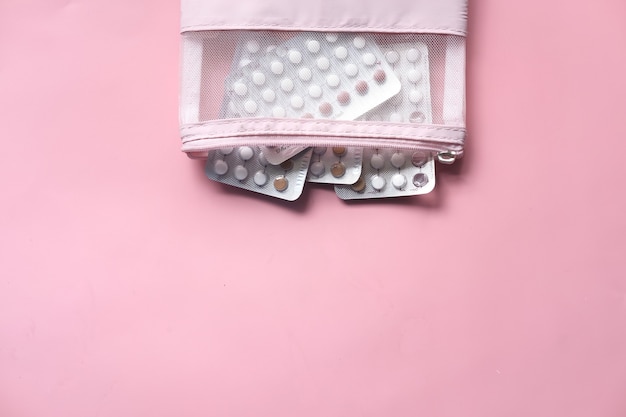 Pilules contraceptives sur fond rose, vue de dessus,