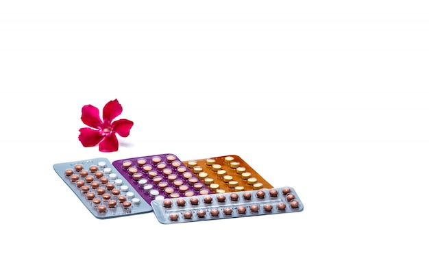 Pilules contraceptives ou pilules contraceptives avec fleur rose isolé sur fond blanc. Hormone pour la contraception. Concept de planification familiale. Comprimés hormonaux ronds sous blister. Acné hormonale.