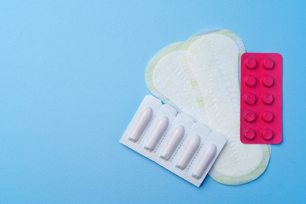 Pilules contraceptives, serviettes hygiéniques et tampons sur fond bleu