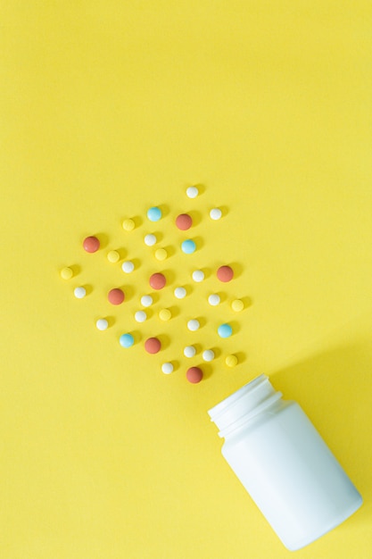 Pilules et flacons de pilules sur fond jaune