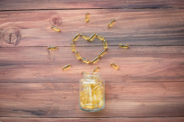 Des pilules en forme de coeur sont tombées d'une bouteille sur une table en bois.