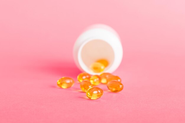 Pilules de gels mous avec de l'huile Omega3 débordant de la bouteille de pilules gros plan Capsules de gel bouteille surface blanche Multivitamines oméga 3 Antibiotiques calciques Santé Immunité